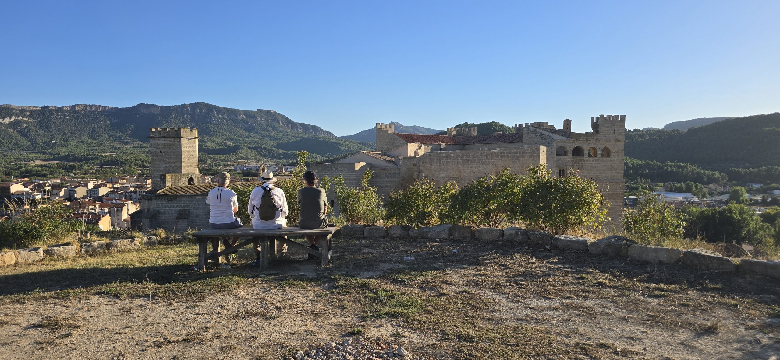 Drei Personen sitzen mit Blick auf die Burg von Valderrobres